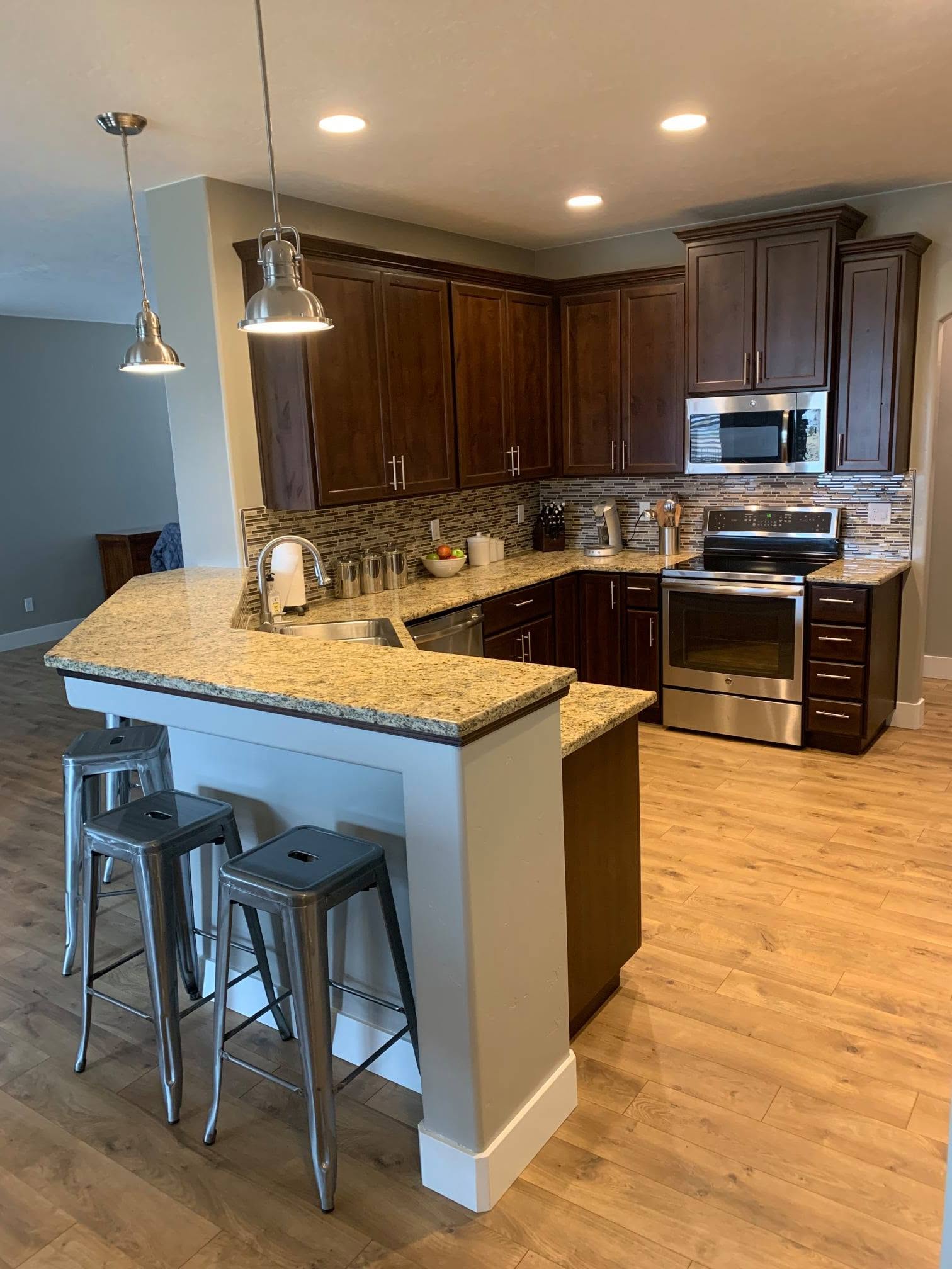 Kitchen and living-space project from the HadCo portfolio, featuring dark cabinetry, a breakfast bar and wood-look flooring
