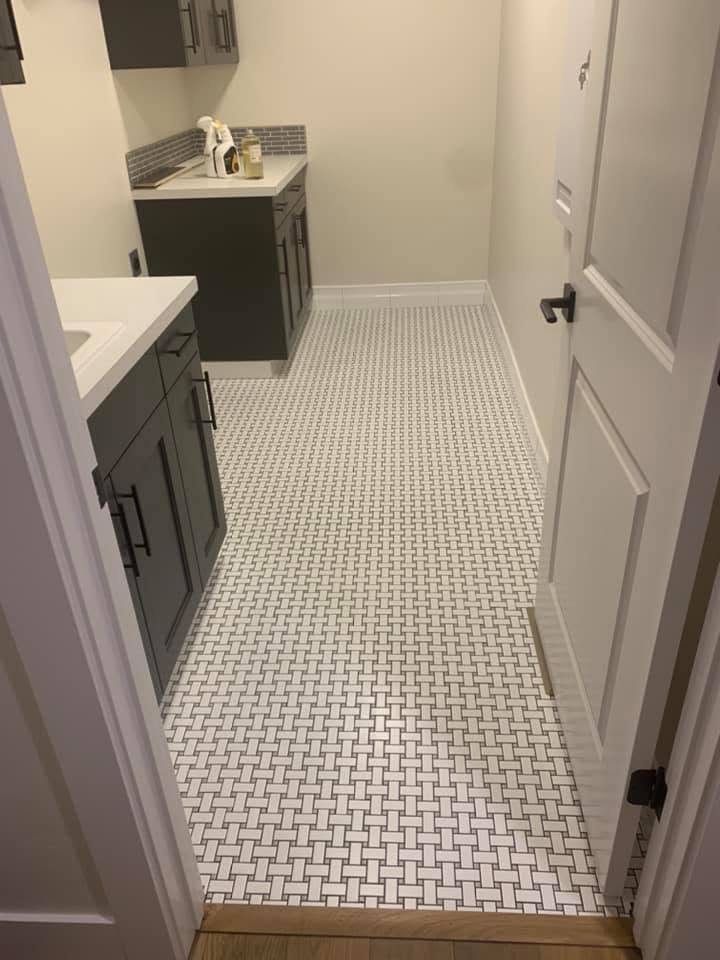 Laundry room with a basketweave mosaic tile floor, dark cabinets, white countertops and a wood threshold.
