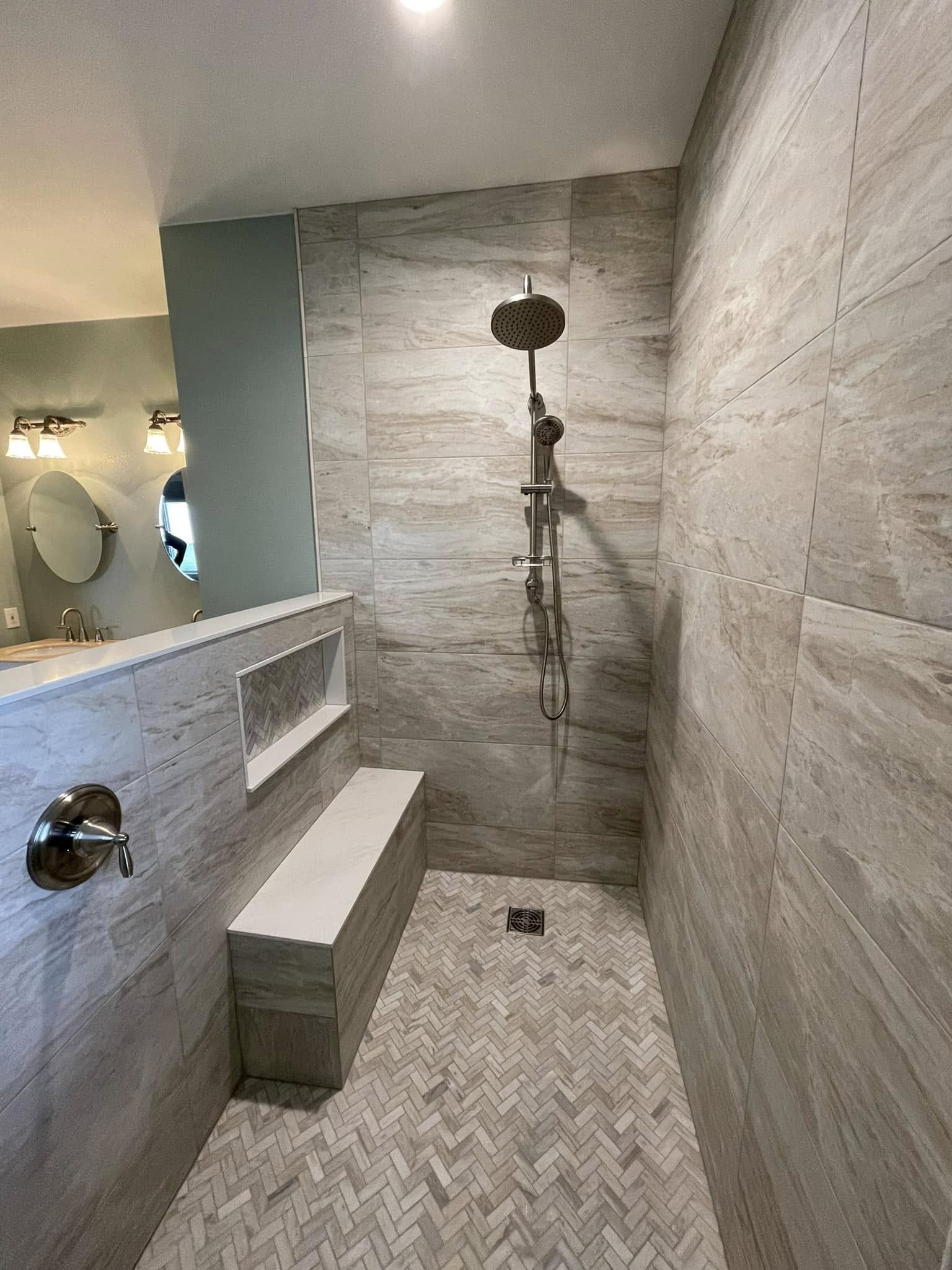 Custom shower niche above a built-in bench with herringbone floor tile