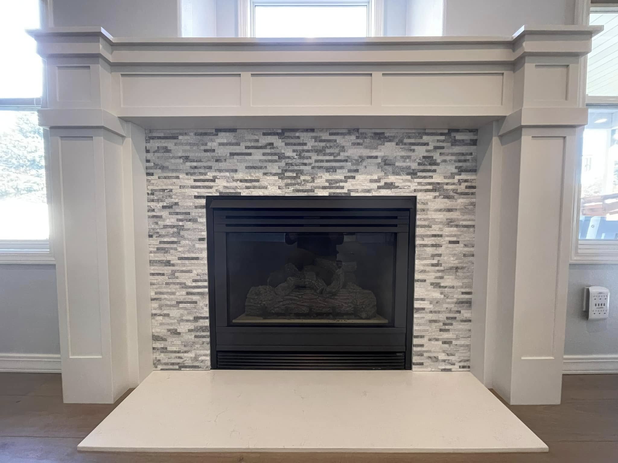 Finished white paneled fireplace mantel with gray mosaic surround and light hearth