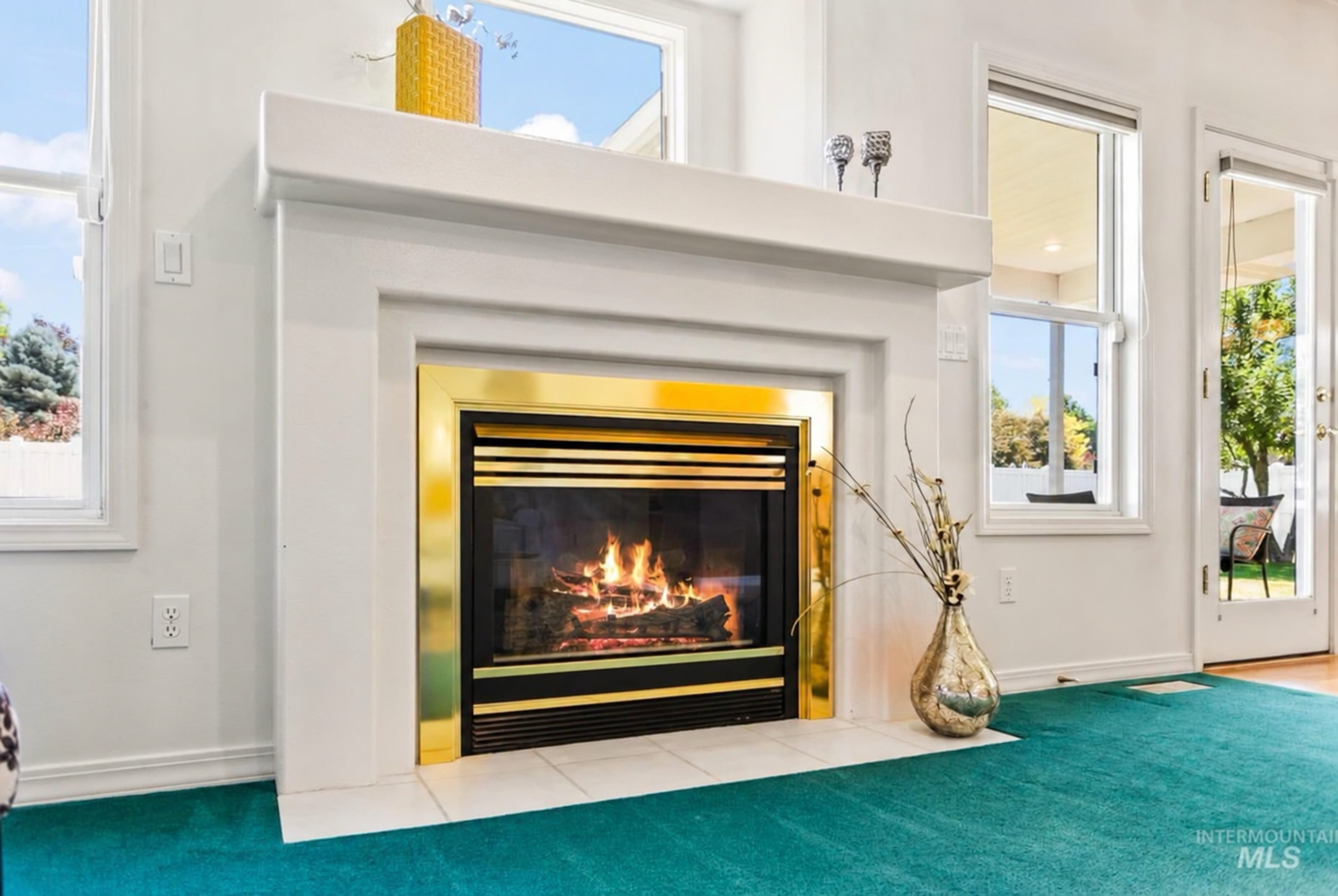 Before: simple white fireplace surround with brass trim and teal carpet