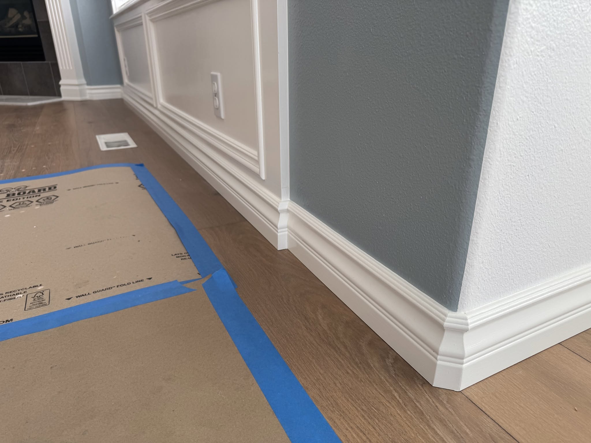 White baseboards and decorative wall trim against blue-gray walls and wood flooring.